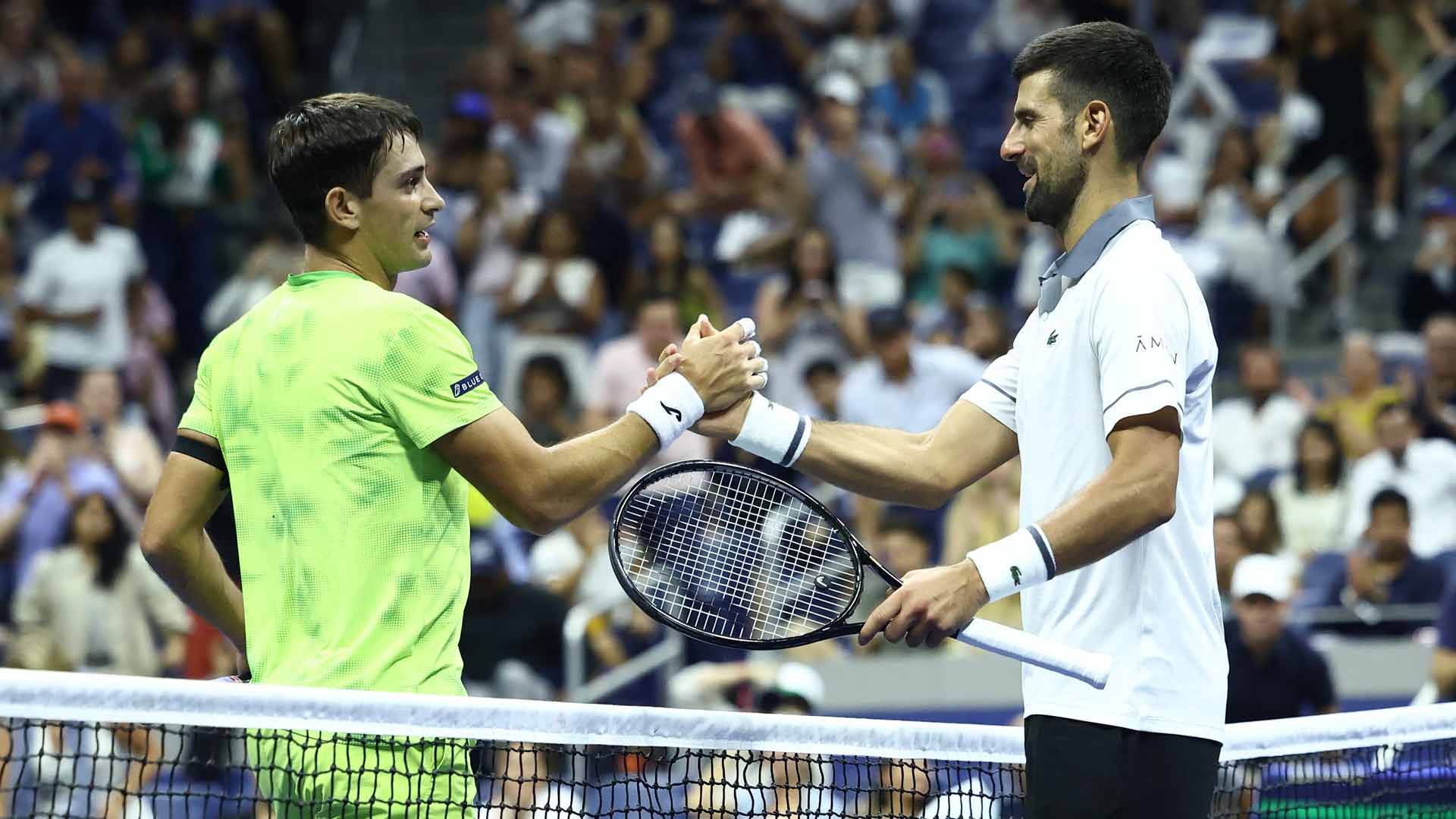Mariano Navone and Novak Djokovic share a moment at net following Navone's five-set victory Sunday evening at the US Open.